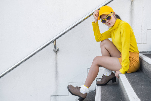 Portrait of beautiful asian woman in yellow cloths,Hipsters girl wear yellow hat on stair for take a picture,Thailand people in yellow tone style - Photo, Image