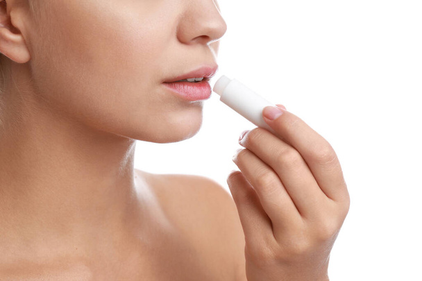 Mujer joven con herpes labial aplicando bálsamo labial sobre fondo blanco, primer plano
 - Foto, Imagen