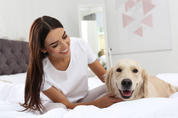 Young woman and her Golden Retriever dog on bed at home - Foto, immagini