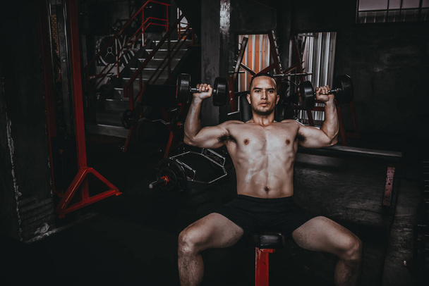 Portrait of asian man big muscle at the gym,Thailand people,Workout for good healthy,Body weight training,Fitness at the gym concept,Prank to abdominal muscles,Lift up dumpbell - Foto, Imagen