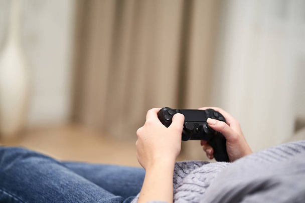 POV Woman lying on the coach in front of TV and holding in hands wireless game controller. Game addiction concept. - Foto, Bild