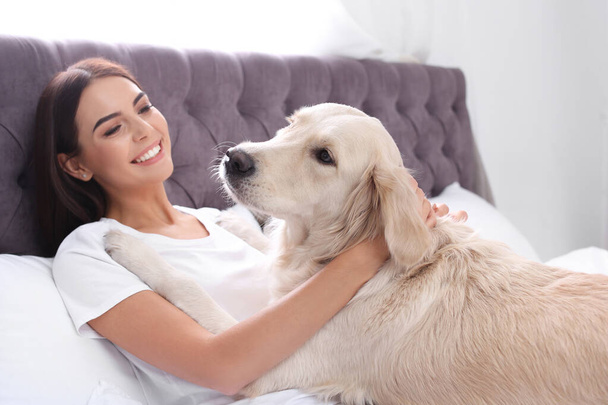 Young woman and her Golden Retriever dog on bed at home - Photo, Image