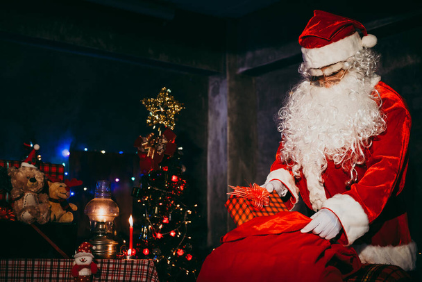 Santa Claus drží dárkovou krabici a otevřený červený pytel pro pohledy, Veselé Vánoce, Štěstí pro děti, Vítejte v zimě, Šťastný nový rok, světlo z tašky - Fotografie, Obrázek