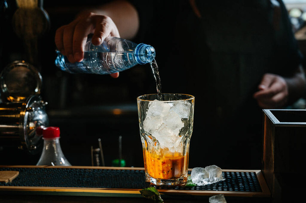 hand bartender make cocktail. Cocktail have orange and mint leaves. - Fotoğraf, Görsel