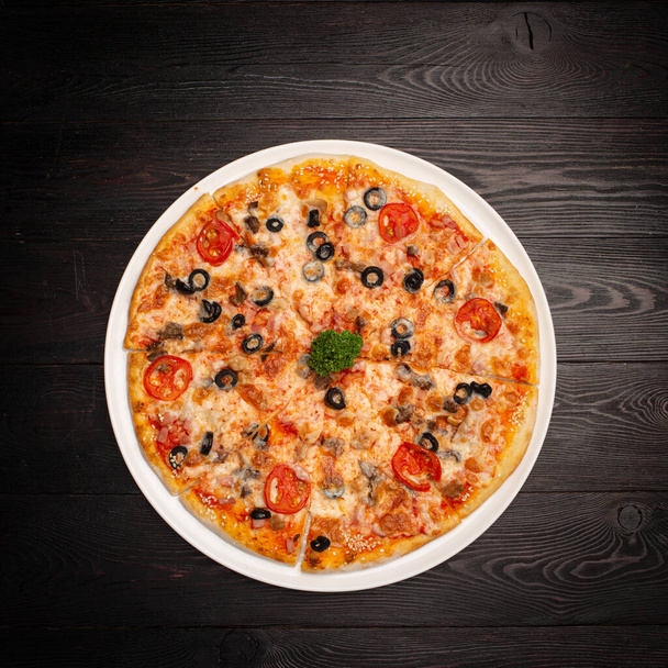 assorted pizza sliced into pieces with cheese, tomato and olives - Foto, Bild