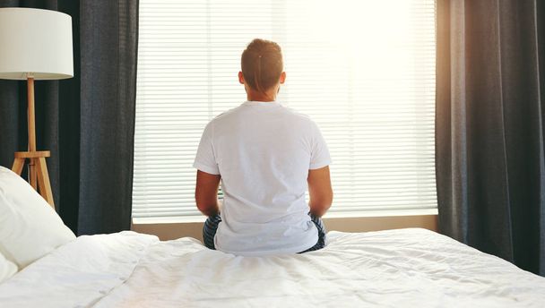 jeune homme assis dos réveillé dans son lit le matin par la fenêtre
 - Photo, image