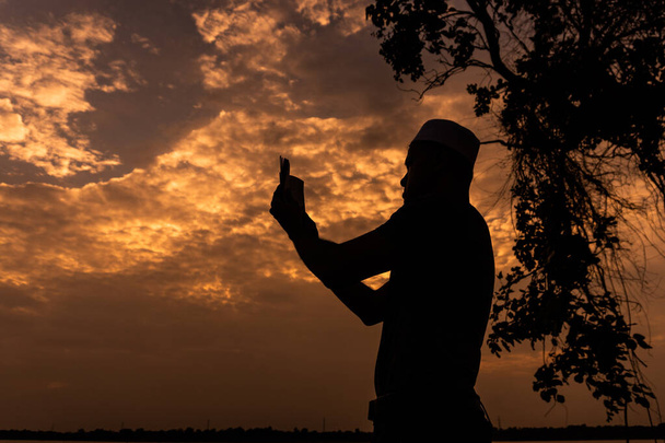 Silhouette Fiatal ázsiai muszlim férfi imádkozik naplemente, Ramadan fesztivál koncepció - Fotó, kép