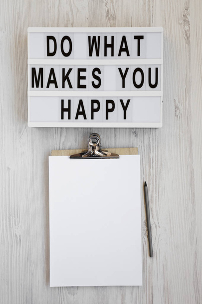 "Tu, was dich glücklich macht" Worte auf einem Leuchtkasten, Klemmbrett mit bl - Foto, Bild