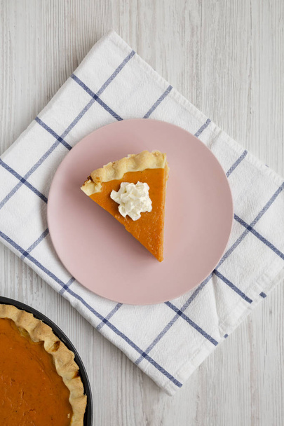 Homemade Thanksgiving pumpkin pie on a pink plate on a white woo - Foto, afbeelding