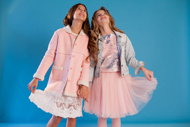 портрет двох красивих модних дівчат у біло-рожевому одязі на синьому фоні
 - Фото, зображення