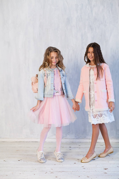 portré két gyönyörű divatos lányok fehér rózsaszín ruhák szürke háttér - Fotó, kép