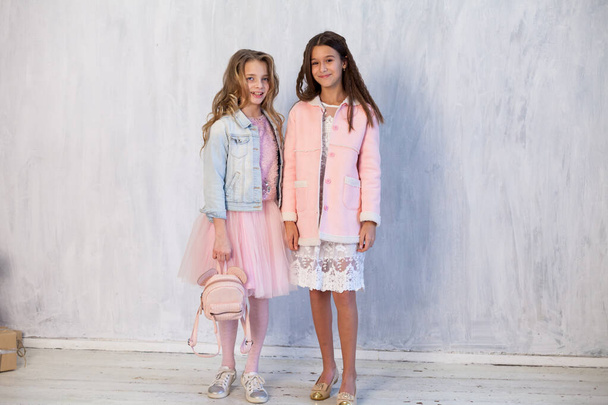 portré két gyönyörű divatos lányok fehér rózsaszín ruhák szürke háttér - Fotó, kép