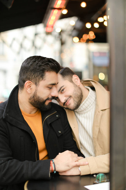 Twee vrolijke blanke homo 's zitten en knuffelen, hand in hand. - Foto, afbeelding