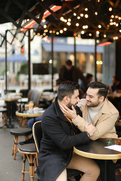 Caucasian happy gays sitting at cafe and hugging. - Photo, Image