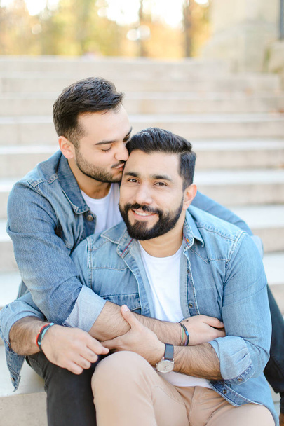 Кавказские геи сидят на бетонной лестнице и целуются
. - Фото, изображение