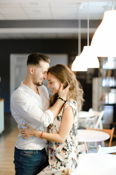 Молодой симпатичный мужчина обнимает женщину и стоит в кафе
. - Фото, изображение