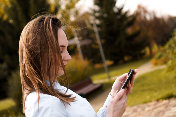 Mulher usando telefone celular inteligente no parque
 - Foto, Imagem