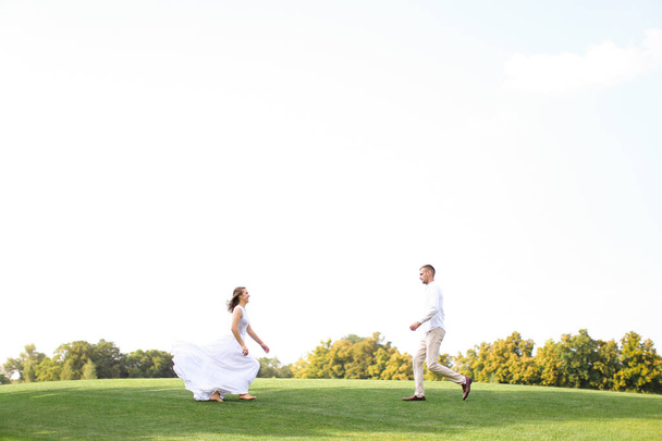 Novia y novio corriendo el uno al otro en la hierba en el fondo del cielo blanco
. - Foto, imagen