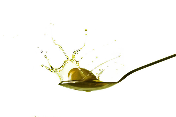 kapky získané z olivy, která padá na lžíci olivového oleje izolované na bílém - Fotografie, Obrázek