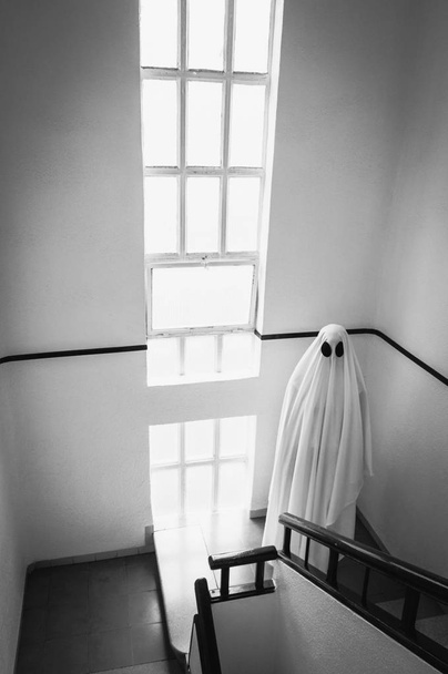 Hayalet, terk edilmiş bir akıl hastanesinin merdivenlerinde beyaz bir hayalet çarşafı ile kaplıydı. Cadılar Bayramı Konsepti - Fotoğraf, Görsel