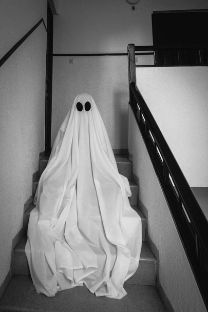 Hayalet, terk edilmiş bir akıl hastanesinin merdivenlerinde beyaz bir hayalet çarşafı ile kaplıydı. Cadılar Bayramı Konsepti - Fotoğraf, Görsel
