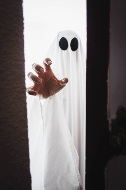 Ghost covered with a white ghost sheet behind the door. Halloween Concept - Fotoğraf, Görsel