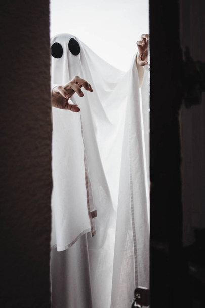 Ghost covered with a white ghost sheet behind the door. Halloween Concept - 写真・画像