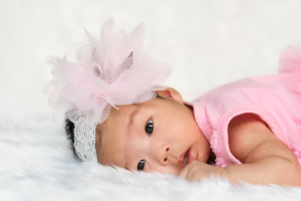 Closeup cute asian baby in pink dress On the carpet wool - 写真・画像