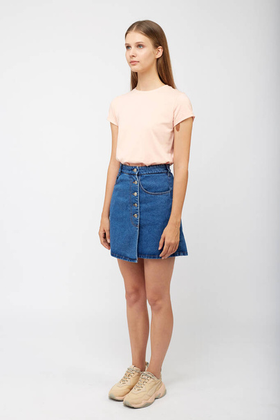 Teenager girl in a denim blue skirt on a white background. - Foto, afbeelding