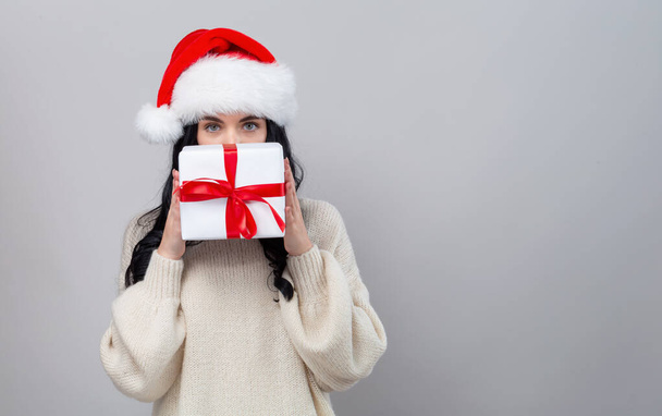 Young woman with santa hat holding a gift box - Foto, Bild