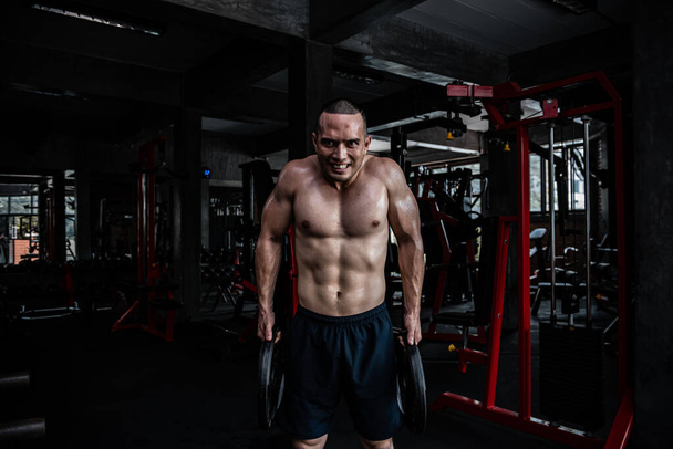 Portrait of asian man big muscle at the gym,Thailand people,Workout for good healthy,Body weight training,Fitness at the gym concept,Prank to abdominal muscles,Lift up heavy steel plate - Fotografie, Obrázek