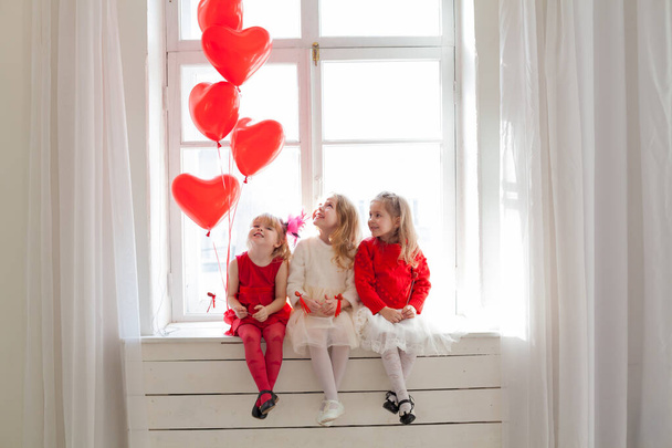 Kalp şeklinde kırmızı balonları olan üç küçük kız. - Fotoğraf, Görsel