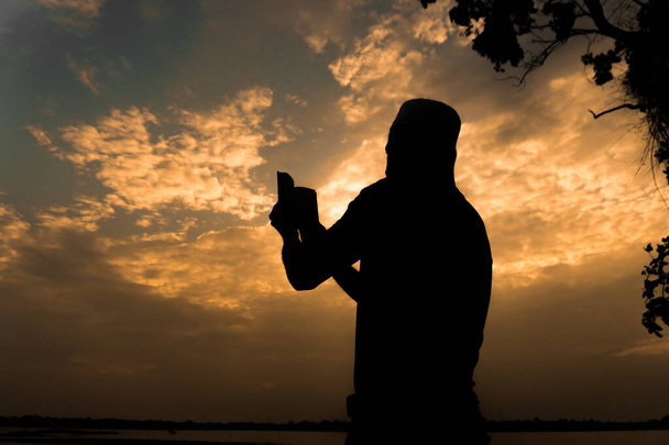 Siluetti Nuori aasialainen muslimi mies rukoilee auringonlaskun, Ramadan festivaali käsite
 - Valokuva, kuva