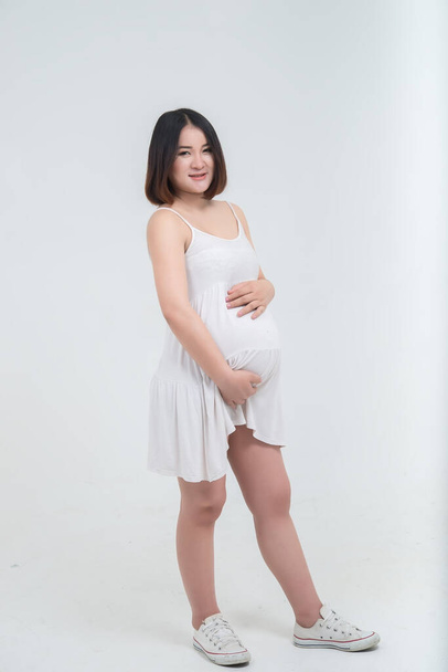 Portret van Aziatische zwangere vrouw op witte achtergrond, Thailand mensen gebruiken hand aanraking buik - Foto, afbeelding