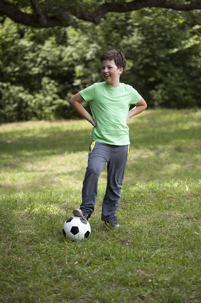 Teen child soccer player. Football Boy with ball on green grass. - Photo, image