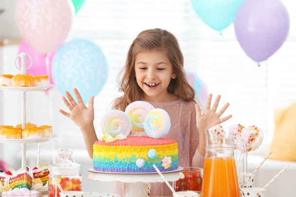 Chica feliz en la mesa con golosinas en la habitación decorada para la fiesta de cumpleaños
 - Foto, imagen