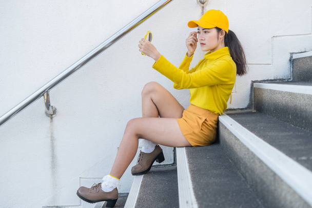 Portrait of beautiful asian woman in yellow cloths,Hipsters girl wear yellow hat sit on stair for take a picture,Thailand people - Foto, imagen