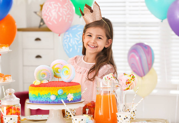 Happy girl at table with treats in room decorated for birthday party - Photo, image