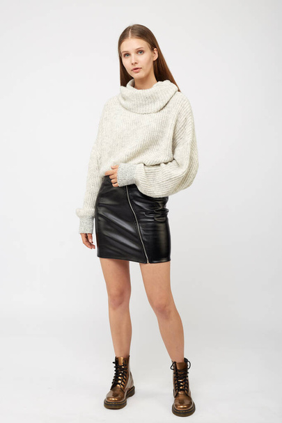 A girl dressed in a white sweater and a black eco-leather skirt - Zdjęcie, obraz