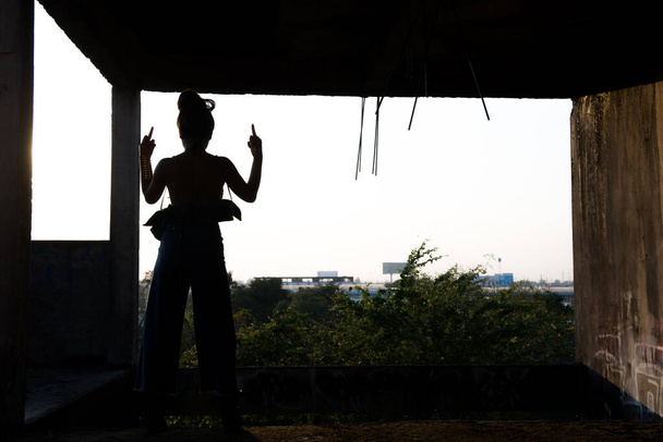 Sylwetka sexy Azji kobieta pokazać środkowy palec w budynku na zachód słońca - Zdjęcie, obraz