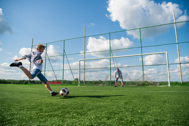 Зображення хлопчика та його батька виглядає щасливим, граючи у футбол у полі
 - Фото, зображення