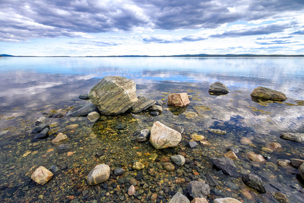 Kameny na břehu zátoky Kandalaksha v Bílém moři. Mraky a obloha se odrážejí ve vodě - Fotografie, Obrázek