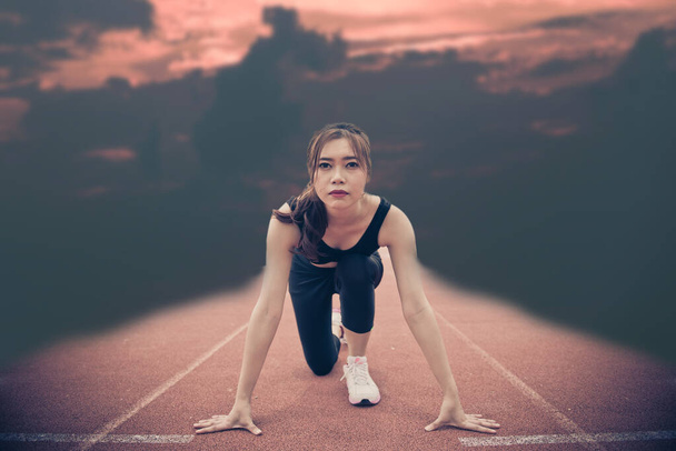 Junge asiatische Frau in einer Position Start auf einer Laufbahn - Foto, Bild