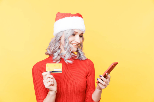 Boże Narodzenie zakupy koncepcji online. Boże Narodzenie dziewczyna trzyma kartę kredytową i telefon. - Zdjęcie, obraz
