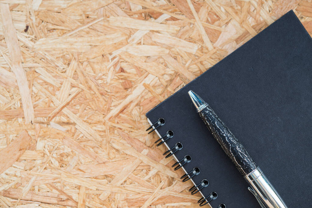 Pen on black notepad on wood background - Foto, Imagen