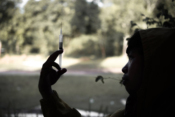 Aasialaisten miesten siluetti on narkomaani, joka ruiskuttaa heroiinia suoniinsa.world anti-drug day käsite
 - Valokuva, kuva