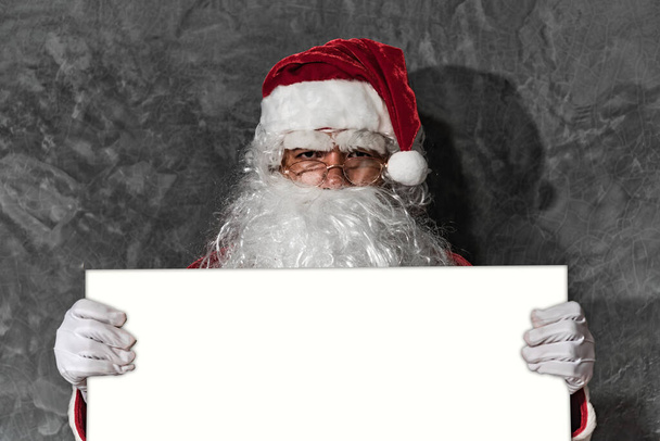 Санта-Клаус вказує руку на білу дошку
 - Фото, зображення