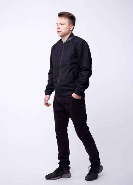 Young man in jeans, black bomber jacket on white background. - Foto, Bild