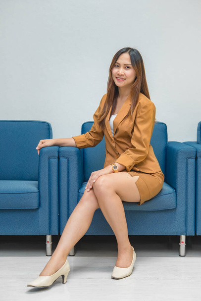 Portrait of beautiful asian business woman wear yellow dress in a office,Thailand people wear ladies uniforms office,Sexy woman on sofa - Фото, изображение