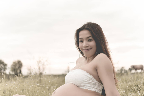 Pregnant woman listen song piano for baby in belly her film tone,vintage,sepia,in the fields,beautiful smile - Foto, afbeelding